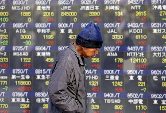 A man walks by an electronic stock board of a securities firm in Tokyo on Thursday. ( AP-Yonhap News)