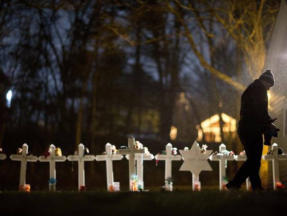 Frank Kulick walks past a display of wooden crosses and a Jewish Star of David, representing the victims of the Sandy Hook Elementary School shooting, on his front lawn on Monday in Newtown, Conn. (AP)