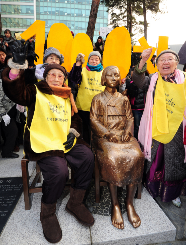 The file photo shows women who were forced into sexual slavery by the Japanese military during the colonization of Korea surrounding the statue erected as a symbol of their suffering during the 1,000th rally outside the Japanese Embassy in Seoul on Dec. 14. (Chung Hee-cho/The Korea Herald)