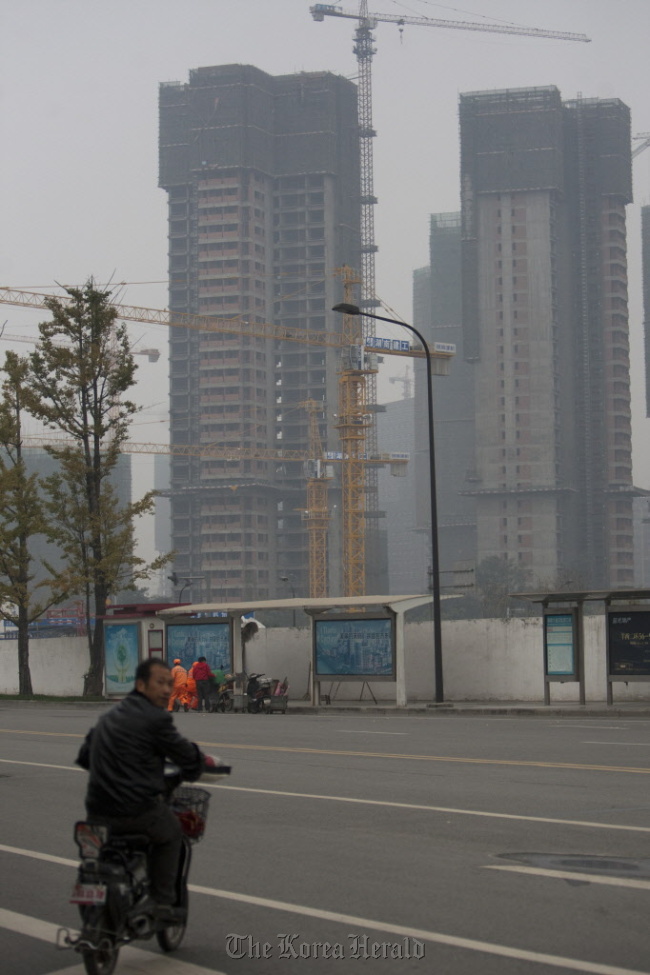 A man on a motorbike checks traffic as construction cranes operate in the Financial City district of Chengdu, Sichuan Province, China. (Bloomberg)