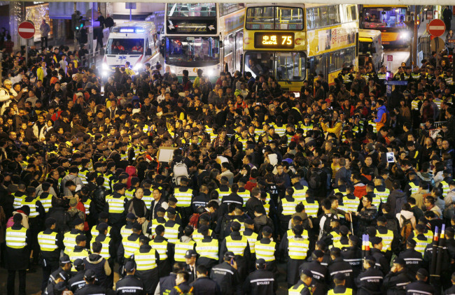 Anti-government protesters, surrounded by police officers, block the main road in Hong Kong on Tuesday to call for the resignation of Hong Kong Chief Executive Leung Chun-ying. (AP-Yonhap News)