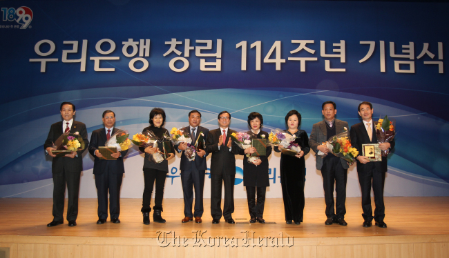 Woori Bank president & CEO Lee Soon-woo (center) poses with customers during an event to celebrate the 114th anniversary of the financial firm’s foundation at its headquarters in downtown Seoul on Friday. Its former entity was Daehan Cheonil Bank, established in 1899 with funds from then-Korean Emperor Gojong. (Woori Bank)