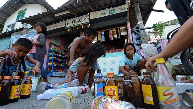 Thai children select used bottles and cans before trading them at a “zero baht shop” in Bangkok. (AFP-Yonhap News)