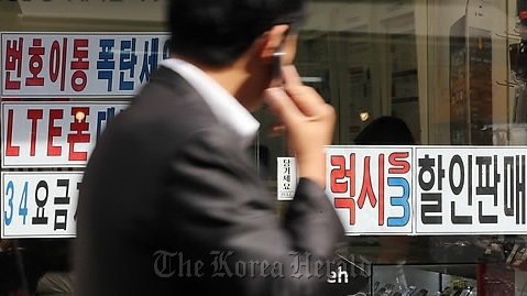 A man walks past a mobile phone shop in Seoul. (Yonhap News)