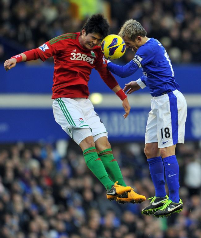 Swansea City’s Ki Sung-yueng (left) and Everton’s Phil Neville challenge for the ball on Saturday. ( AFP-Yonhap News)