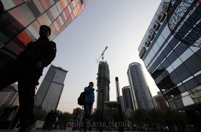 Pedestrians walk past commercial buildings in the Sanlitun area of Beijing. (Bloomberg)