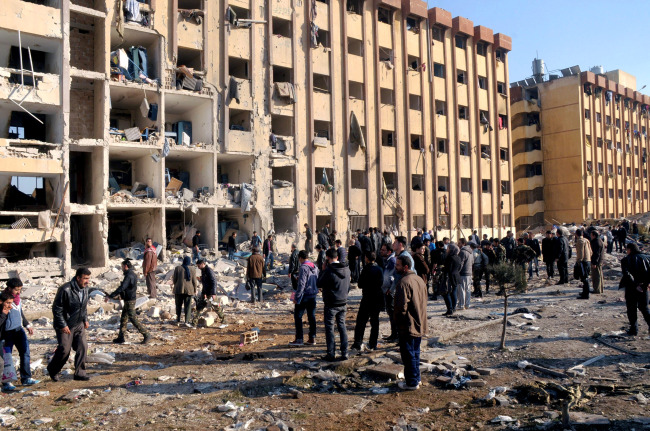 Syrian people gather at the site after an explosion hit a university in Aleppo, Syria, Tuesday. (AP-Yonhap News)