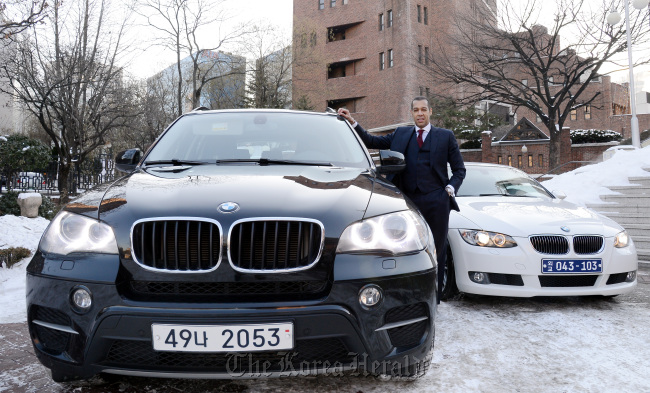 Ernesto Torres-Pereyera stands between the BMW X5 and his own BMW 328i convertible in the Jeong-dong area, central Seoul. (Ahn Hoon/The Korea Herald)