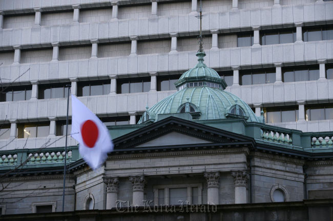 The Japanese national flag flies atop the Bank of Japan headquarters in Tokyo. (Bloomberg)