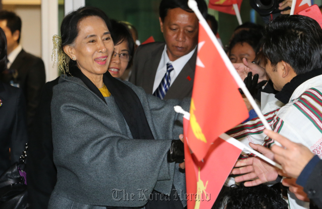 Myanmar`s opposition leader Aung San Suu Kyi greets with her countrymen upon her arrival at Incheon International Airport in Korea late Monday. (Yonhap News)