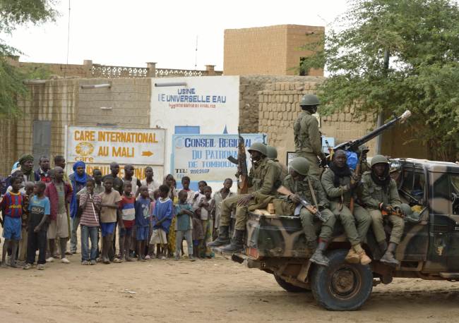 People watch Malian troops as they enter the historic city of Timbuktu, occupied for 10 months by Islamists who imposed a harsh form of sharia, Monday. (AFP-Yonhap News)