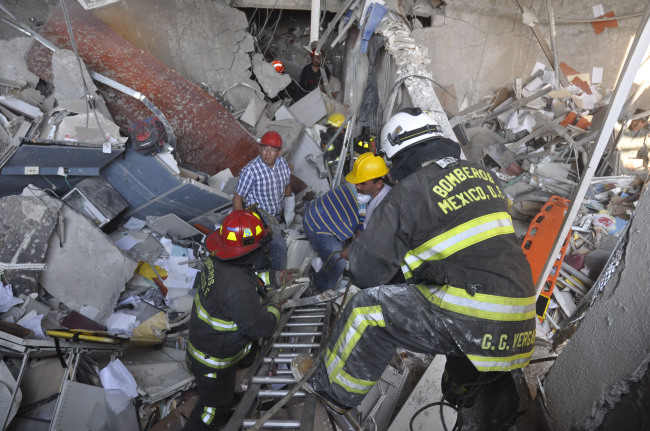 Firefighters belonging to the Tacubaya sector and workers dig for survivors after an explosion at a building adjacent to the executive tower of Mexico’s state-owned oil company PEMEX in Mexico City on Thursday. ( AP-Yonhap News)