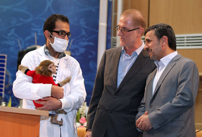 Iranian President Mahmoud Ahmadinejad (right) looks at a space monkey during a ceremony to mark Iran’s National Day of Space Technology in Tehran on Monday. (AFP-Yonhap News)