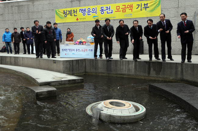 Officials from the Korean Committee for UNICEF, a committee to manage palseokdam coins, Seoul Metropolitan Facilities Management Corp. and Community Chest of Korea throw coins into palseokdam during a coin donation ceremony in Seoul on Tuesday. (Yonhap News)