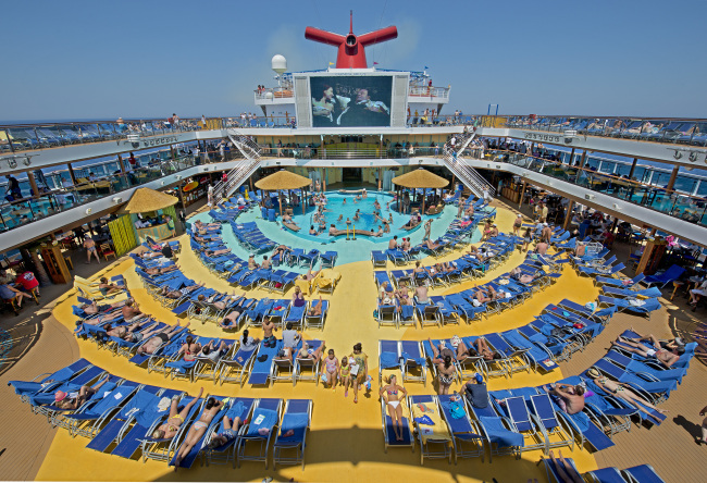 In this June 23, 2012 photo provided by Carnival Cruise Lines, vacationers aboard the Carnival Breeze enjoy sunbathing at sea while watching a movie at the Carnival’s Seaside Theatre. (AP-Yonhap News)