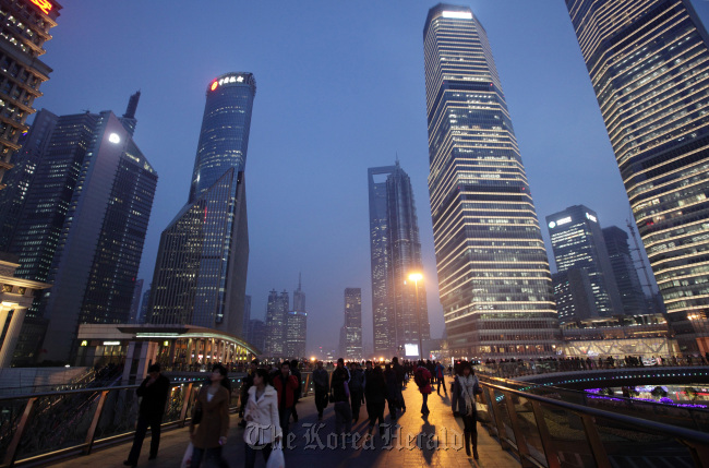 Pedestrians and workers walk on an overpass past commercial buildings at dusk in the Pudong area of Shanghai. (Bloomberg)