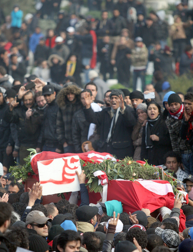 The coffin, wrapped in the Tunisian red flag, of slain opposition leader Chokri Belaid is carried at el Jallez cemetery while thousands attend his funeral near Tunis, Friday. (AP-Yonhap News)