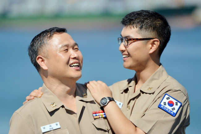 Warrant Officer Nam Dae-il (left), 52, joins his son Petty Officer 2nd Class Nam Hyun-jae, 22, aboard Munmu the Great, a Korean-made 4,400-ton destroyer of the anti-piracy Cheonghae Unit off Somalia on Sunday. (Joint Chiefs of Staff)
