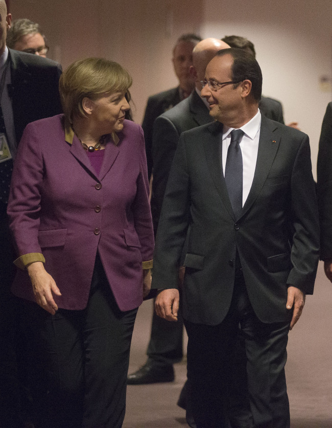 German Chancelor Angela Merkel (left) and French President Francois Hollande arrive for their press conferences at the European Council building in Brussels on Friday. ( AP-Yonhap News)