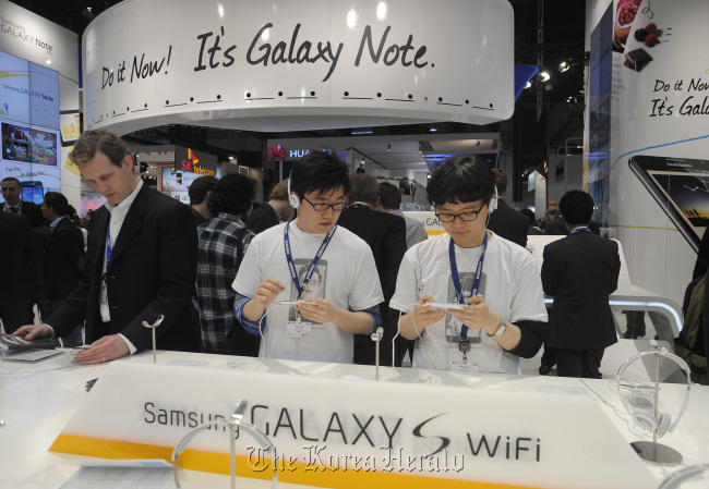 Visitors inspect Samsung Electronics Co. Galaxy S smartphones on display at the Mobile World Congress in Barcelona, Spain, February 2012. (Bloomberg)