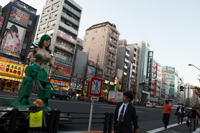 A pedestrian looks at a promotional statue displayed by the side of a road in the district of Akihabara in Tokyo. (Bloomberg)