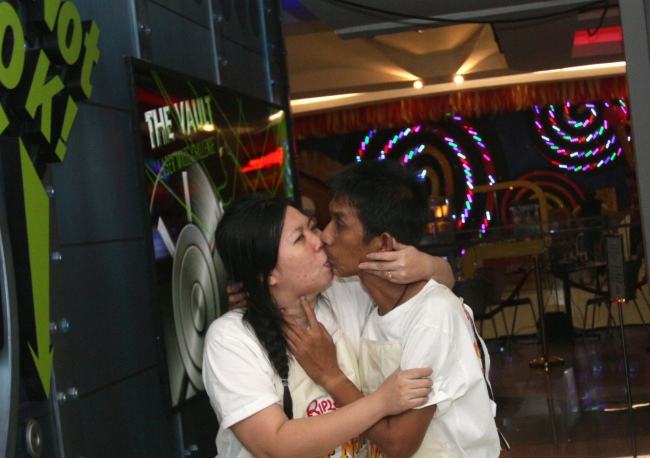 kkachai Tiranarat, center, and Laksana Tiranarat walk to the restroom during the World`s Longest Continuous Kiss Competition in Pattaya, southeastern Thailand, Thursday. (AP-Yonhap News)