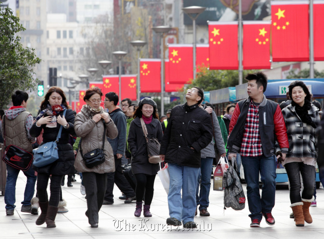 Chinese flags hang on lamp posts as pedestrians walk through the East Nanjing Road shopping area of Shanghai. (Bloomberg)