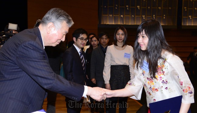 Booyoung Group chairman Lee Joong-keun (left) awards a scholarship to a student at a ceremony in Seoul on Monday. (Park Hae-mook/The Korea Herald)