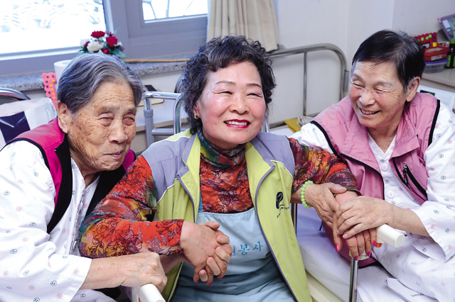 Kang Cheol-ye (center) poses with elderly women at Indeokwon nursing home. (Park Hae-mook/The Korea Herald)