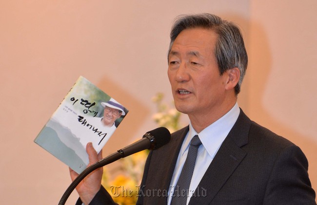 Asan Foundation chairman Chung Mong-joon holds a copy of an autobiography of his late father Chung Ju-yung, who established the foundation, while speaking at a ceremony to deliver scholarships to students at the Asan Institute for Life Sciences in Seoul on Thursday. (Lee Sang-sub/The Korea Herald)