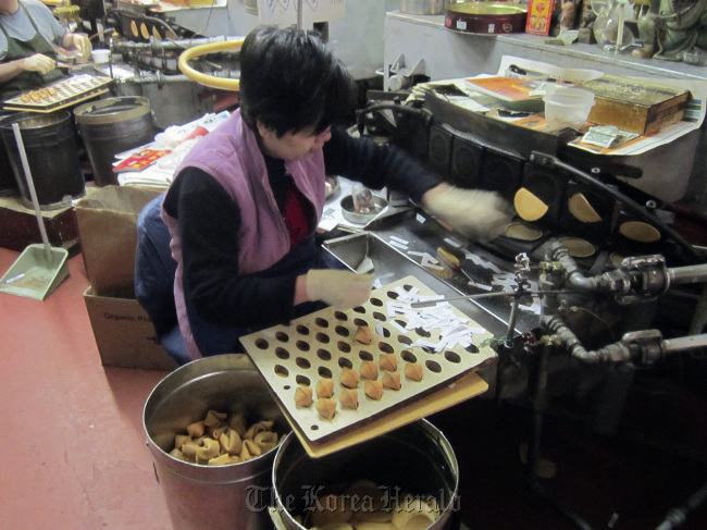 A woman deftly folds and inserts fortunes into cooling cookies at the Golden Gate Fortune Cookie Company, which produces 20,000 handmade fortune cookies a day in San Francisco’s Chinatown. (Chicago Tribune/MCT)