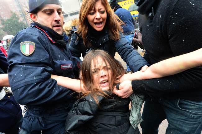 A protester is arrested by riot policemen outside the polling station where former Prime Minister Silvio Berlusconi cast his ballot in Milan on Sunday. ( AFP-Yonhap News)