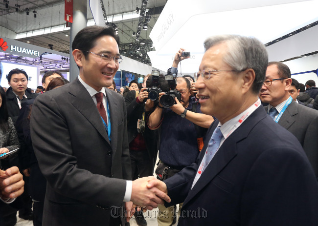 Samsung Electronics vice chairman Lee Jay-yong (left) shakes hands with KT chairman Lee Suk-chae at the Mobile World Congress in Barcelona on Monday. (Samsung Electronics)