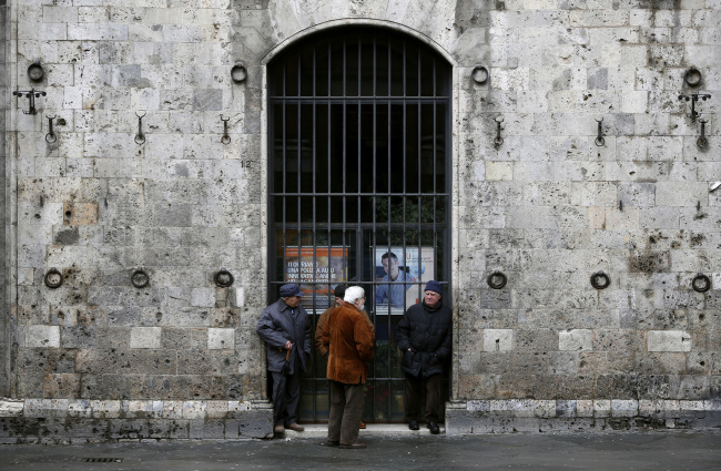 Pedestrians stand and chat outside a shuttered branch of Intesa Sanpaolo SpA bank in Siena, Italy. (Bloomberg)