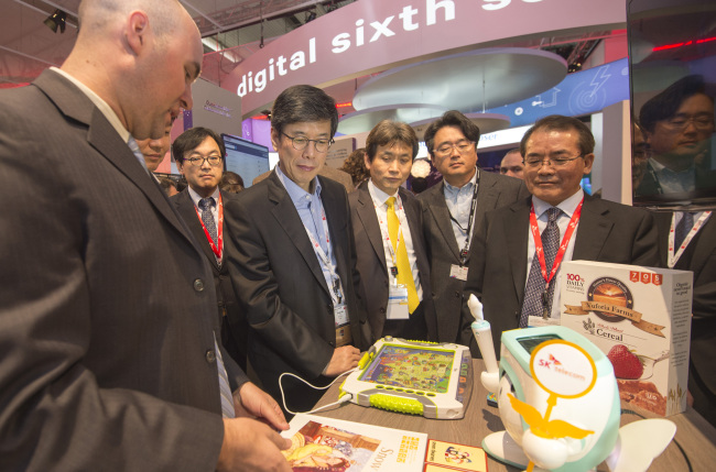 SK Telecom CEO Ha Sung-min (left) looks at educational robot “Atti” unveiled by the company at the Mobile World Congress on Monday. (Joint Press Corps)