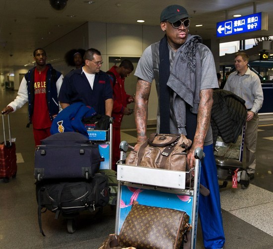 Former NBA star Dennis Rodman, right, and three members of the Harlem Globetrotters basketball team, seen at back, prepare to check in at the departure hall of Beijing Capital International Airport in Beijing Tuesday. (AP-Yonhap News)