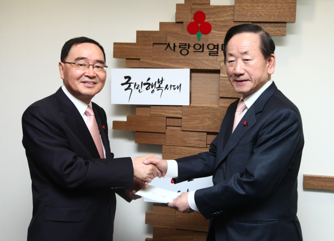 Prime Minister Chong Hong-won (left) delivers his donation to Lee Dong-kurn, chairman of the Community Chest of Korea, at the charitable organization in Seoul on Wednesday. (Community Chest of Korea)