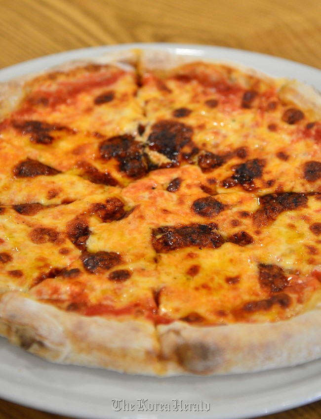 Fresh out of the wood-fired oven, chef Paolo De Maria’s Margherita pizza is a perfect marriage of crust, tomato and cheese. (Lee Sang-sub/The Korea Herald)