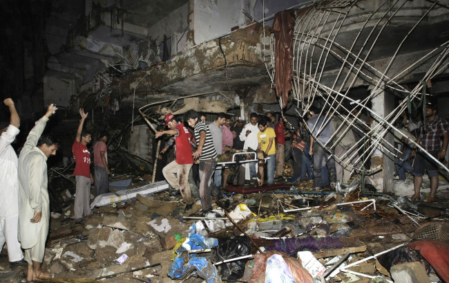 Pakistani medics carry the lifeless body of a man from the site of a bomb blast in Karachi, Pakistan, Sunday. (AP-Yonhap News)