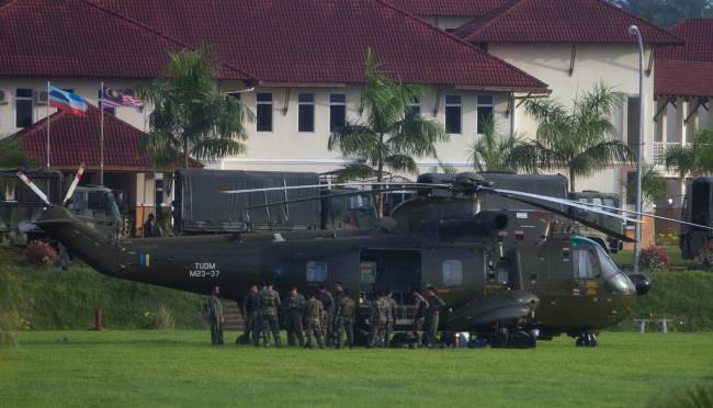 Officers stand by a Royal Malaysian Air Force Sikorsky S-61 helicopter in Cenderawasih, Malaysia, Tuesday. (AFP-Yonhap News)