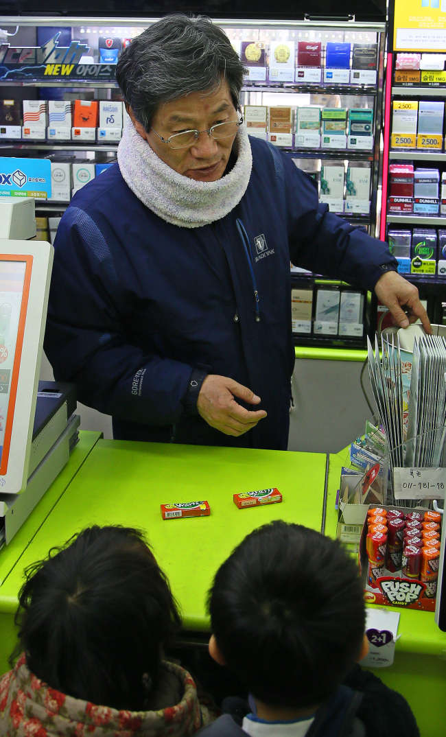 Kim Neung-hwan, former Supreme Court justice and chairman of the National Election Commission, works at a checkout counter of his wife’s convenience store in Dongjak-gu, Seoul Wednesday. (Yonhap News)