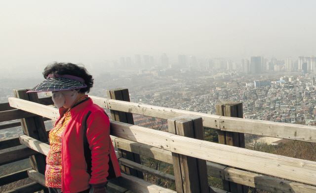 This Feb. 28 photo shows a woman with a facial mask standing on the top of Namsan Mountain in central Seoul when yellow dust from western China reached the city. (Yonhap News)