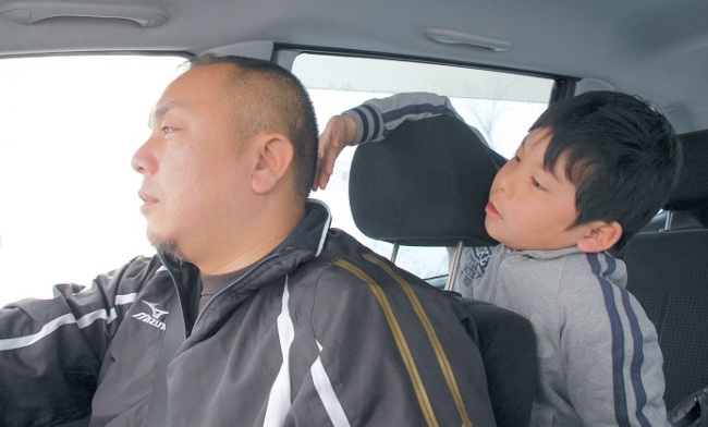 Takahiro Ishitani drives a car as his son touches his head as they go shopping during his weekend stay in Iide, Yamagata prefecture, Japan. (AP-Yonhap News)