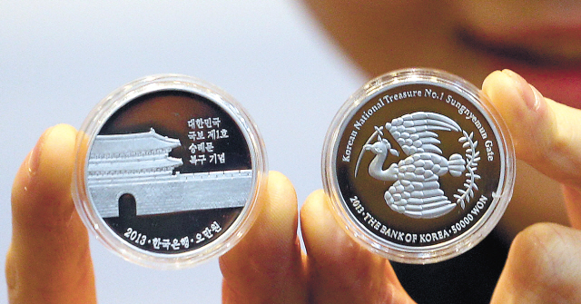 A model shows prototype commemoration coins for the upcoming unveiling of Sungnyemun, which is national treasure No. 1, at the Currency Museum of the Bank of Korea in Seoul on Monday. (Yonhap News)