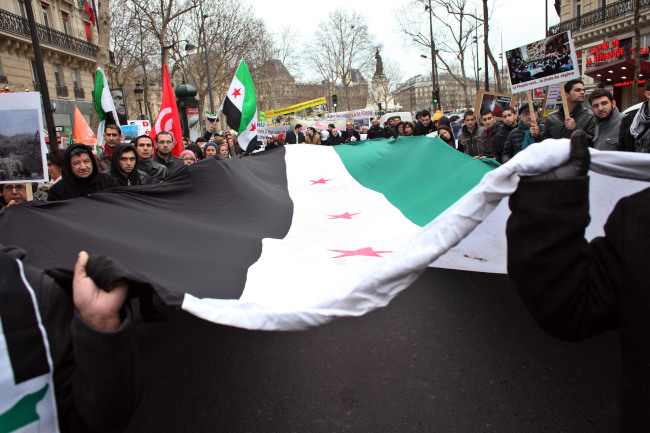 Demonstrators hold a giant Syrian flag during a march to mark the second anniversary of the revolt against Syrian President Bashar Assad’s government in Paris on Saturday. (AFP-Yonhap News)