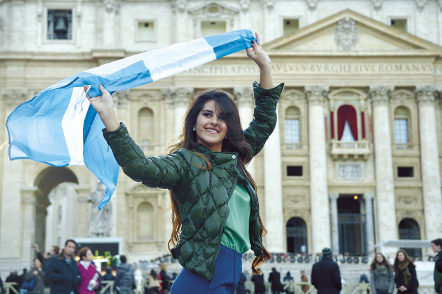 A woman poses with an Argentine flag in St. Peter’s square at the Vatican on Thursday, a day after the election of the new pope. (AFP-Yonhap News)