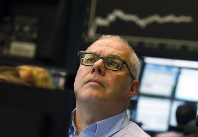 A trader monitors financial data on his computer screens beneath a display of the DAX Index curve at the Frankfurt Stock Exchange in Frankfurt on Monday. (Bloomberg)