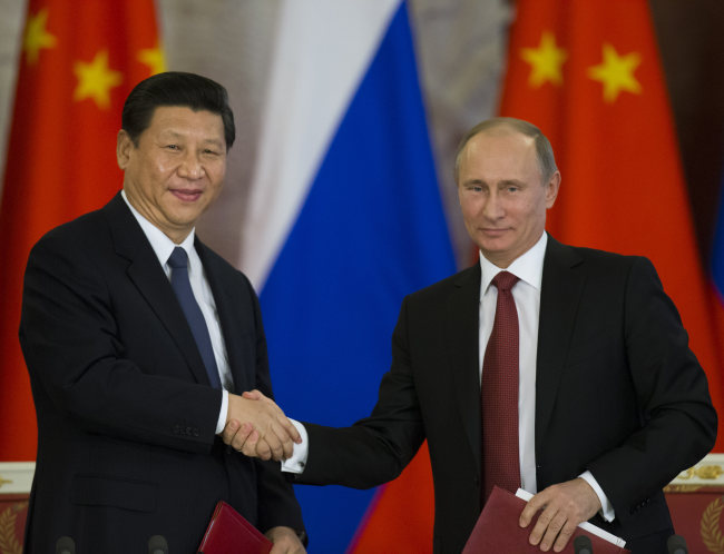 Russian President Vladimir Putin (right) and Chinese President Xi Jinping shake hands as they exchange documents after their talks in Moscow’s Kremlin on Friday. (AP-Yonhap News)