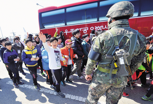 A South Korean soldier stands guard as children walk along a road linked to North Korea at a military check point in Paju near the Demilitarized Zone during a day-long International Children’s Peace Day organized by International Cooperation of Environmental Youth on Thursday. (AFP-Yonhap News)