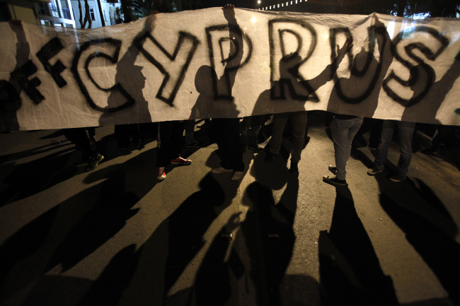 Protesters hold a banner that reads “Hands off Cyprus” during an anti-bailout rally on Sunday. (AP-Yonhap News)